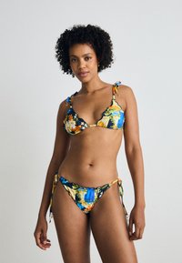 Bikini komplektas su gėlių raštu, kuriame dominuoja mėlyna, geltona ir oranžinė spalvos. Medžiaga lygi; liemenėlės turi plonas juosteles ir banguotus kraštus.