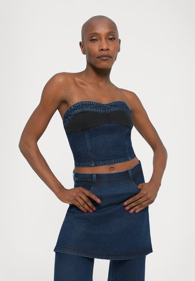 Blue denim strapless top with a textured black accent, featuring a fitted design and cropped length; paired with a matching denim mini skirt.