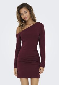 Vestido burdeos con cuello off-the-shoulder, mangas largas, silueta ajustada y detalles ligeramente fruncidos en la cintura para añadir textura.