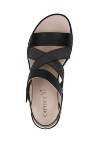 Juoda odinė sandalai su plačiomis kryžminėmis juostomis ir elastingomis detalėmis. Vidpadis šviesiai beige spalvos su iškilniu "CAPRICE" logotipu.