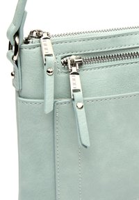 Svetlo modra usnjena torba z več zadrg, srebrno strojno opremo in teksturirano površino. Ima nastavljiv naramnico.