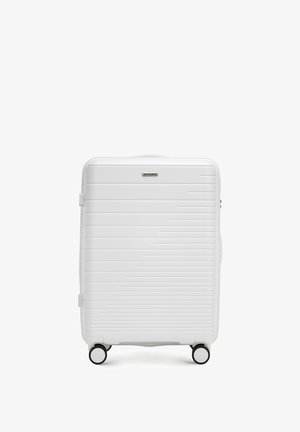 Maleta rígida blanca con ranuras horizontales, ruedas negras y un asa superior. Presenta un logo de la marca en la parte frontal. Forma rectangular.
