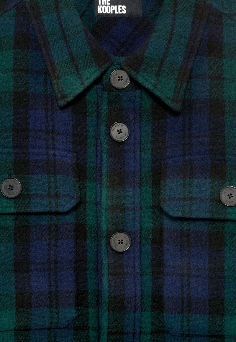 Dunkelgrünes und blaues kariertes Hemd mit schwarzen Knöpfen, die mit "The Kooples" geprägt sind, und zwei Brusttaschen mit Klappen.