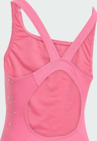 Rosa träningslinne med racerback-design, en slät textur och silverfärgade prickar på sidan.