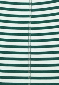 Grön- och vitrandig tyg med en slät textur och ett enhetligt mönster, med synlig sömnad längs mittsömmen.