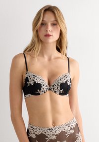 Svart spetsbehå med beige blommig broderi, har formpressade kupor, justerbara axelband och en slät textur. Designad för en modern passform.