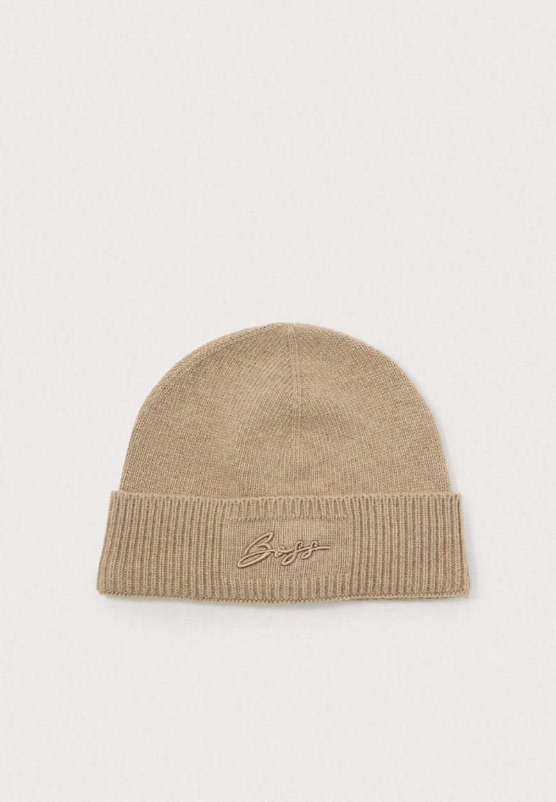 Gorra de punto beige con dobladillo acanalado. Presenta un logo bordado en contraste en la parte frontal. Textura suave y forma redondeada.