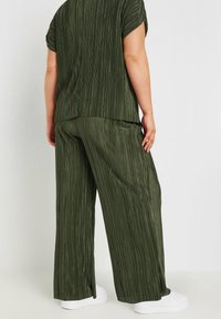 Grönrandig outfit med en löst sittande topp med korta ärmar och vida byxor. Tyget har en texturerad yta. Kombinerad med vita skor.