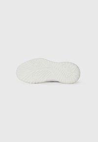 Sålen på en sneaker, overvejende hvid, med et tekstureret mønster med riller og afrundede detaljer for forbedret greb og fleksibilitet.