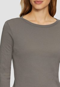 Langarmshirt in gedecktem Grau, aus weichem, dehnbarem Material. Mit einem runden Halsausschnitt und einer taillierten Passform. Glatte Textur, keine Muster.