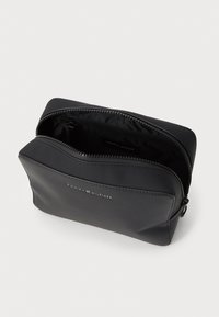 Black leather pouch with zip closure, featuring a smooth exterior and a logo detail on the front. Interior is lined with fabric.