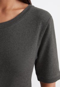 Donkergrijze sweater met een geribbelde ronde halslijn en korte mouwen, gemaakt van een zachte, gestructureerde breikatoen.