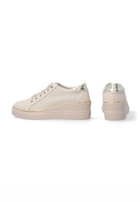 Beige Sneaker mit einem glatten Lederoberteil mit Perforationen, metallischen Akzenten an der Ferse und einer dicken, strukturierten Sohle.