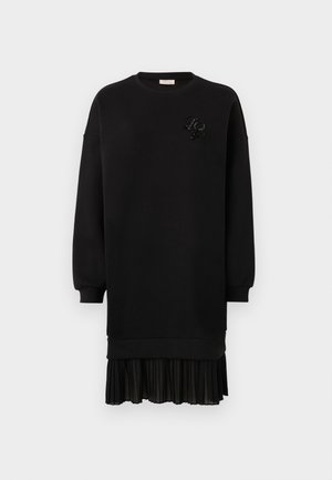 Robe sweat noire en tissu doux, avec un ourlet de jupe plissée et un détail décoratif en perles sur la poitrine. Manches longues.