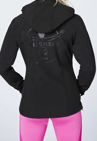 Czarna bluza z kapturem, z refleksyjnym logo na plecach. Gładka tkanina, dopasowany krój i lekki połysk.