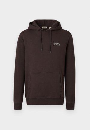 Smeđa dukserica s kangaroo džepom, kapuljačom sa šnuredima i bijelim "Dystopia" logotipom na prednjoj strani. Napravljena od mekog, teksturiranog materijala.