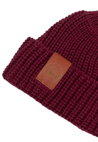 Bordowy dzianinowy beanie z żebrową teksturą i brązową skórzaną łatą z zielonym logo wyszytym z przodu.
