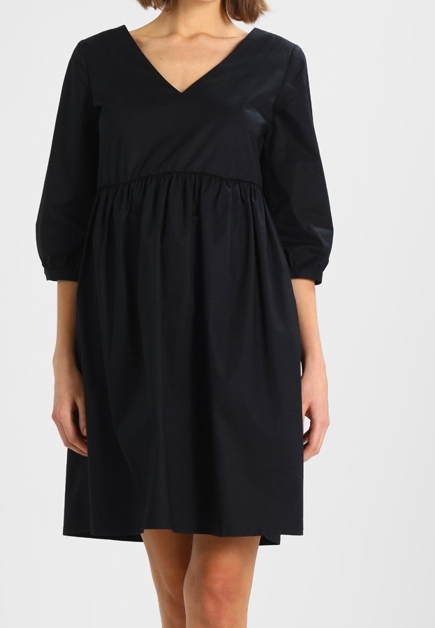 Zwarte jurk met een V-hals, driekwart mouwen en een gerimpelde taille. Gemaakt van katoen met een gladde textuur en een zoom tot op de knie.