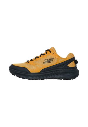 Zapatilla de running de malla amarilla con acentos negros, que presenta una suela acolchada y un patrón texturizado. Cordoneras y tirador incluidos para facilitar el calzado.