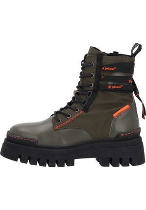 Botas de tobillo de cuero verde oliva, con cordones, que presentan una suela negra gruesa, costuras naranjas y tiras elásticas en el caño.