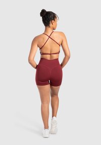 Bordeaux sporttop met kruisbandjes en bijpassende high-waisted shorts. Glad materiaal, aansluitend ontwerp en minimalistische stijl.