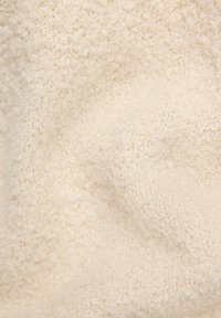 Strukturierter Stoff in Cremeweiß mit einer weichen, flauschigen Oberfläche und dezenten schimmernden Details. Weiches und geschmeidiges Aussehen mit zerknitterter Optik.