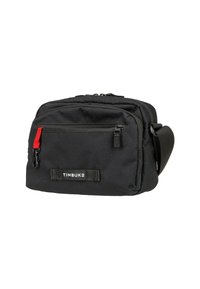 Sac messager en tissu noir avec un compartiment principal à fermeture éclair, une poche frontale à fermeture éclair et un tirant de fermeture éclair rouge. Équipé d'une sangle réglable et d'une étiquette TIMBUK2.