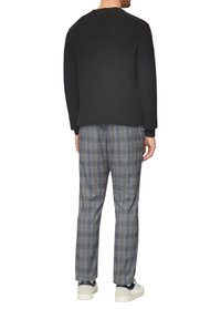 Schwarzer strukturierten Strickpullover kombiniert mit grauen karierten Hosen mit blauen Akzenten. Das Modell trägt weiße Sneaker. Rückansicht des Outfits.