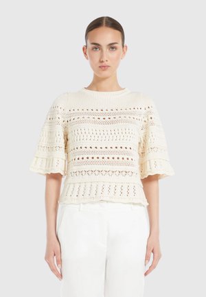 Un haut en tricot crème avec des manches courtes évasées, présentant un motif texturé avec des mailles ouvertes et un ourlet festonné.