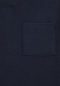 Mornarsko modra teksturirana pletena majica z V-izrezom in žepom na prsih, izdelana iz zračne tkanine z subtilnim vzorcem.