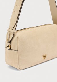 Τσάντα χιαστί από μπεζ σουέντ με επίχρυσες μεταλλικές λεπτομέρειες, φερμουάρ και ρυθμιζόμενο λουράκι. Διαθέτει μινιμαλιστικό σχεδιασμό και διακριτικό ανάγλυφο λογότυπο.