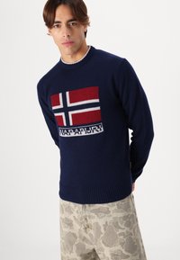 Marineblauer Pullover aus weichem Material mit einem gestrickten norwegischen Flaggenmuster in Rot und Weiß. Rippbündchen und Saum, lässige Passform.