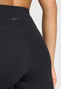 Μαύροι ψηλόμεσοι κολάν από ελαστικό ύφασμα, με λεία υφή και διακριτικό λογότυπο στη ζώνη της μέσης.