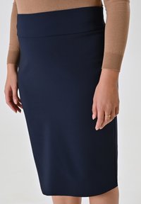 Gonna a matita blu navy in tessuto elasticizzato, con vita alta e una superficie liscia, che arriva appena sotto il ginocchio.