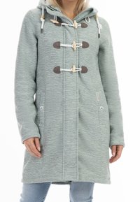 Světlá zelená, texturovaná dlouhá bunda s kapucí, s patentními zapínáními, bočními kapsami a kontrastními hnědými detaily. Materiál ze směsi bavlny.