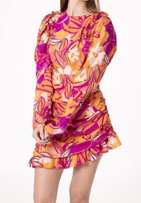 Robe imprimée florale en orange et rose, dotée de manches longues, de volants sur l'ourlet et de détails cintrés sur les côtés pour une silhouette ajustée.