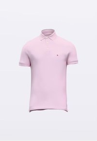 Pehmeä vaaleanpunainen poolopaita, valmistettu joustocollegemateriaalista. Siinä on kaksinappinen kaulus, lyhyet hihat ja pieni kirjailtu logo rinnassa.