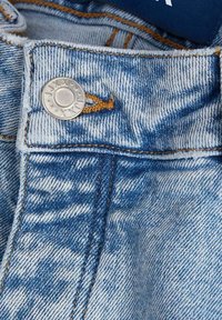 Close-up de jeans de denim azul claro, apresentando um botão prateado, costura laranja e um acabamento texturizado e desbotado ao longo da cintura.