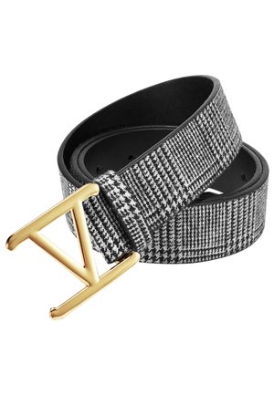 Käärity mustavalkoinen koiranhampaidencolpatternvyö, jossa on kultainen kolmionmuotoinen metallisolki valkoisella taustalla.