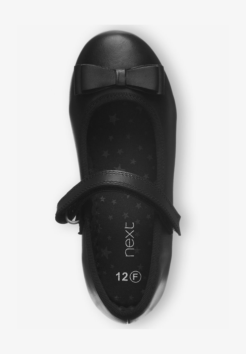 Balerini din piele neagră, cu vârf rotund, prezentând un detaliu sub formă de fundă. Interiorul are un model cu stele, iar o curea cu scai pe lateral asigură o potrivire sigură.