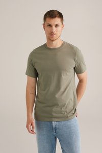 Camiseta de manga corta en verde oliva hecha de algodón suave, con un cuello redondo clásico y un ajuste relajado, combinada con jeans azul claro.