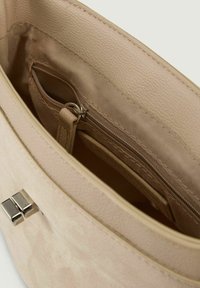 Interno della borsa beige con foderatura in tessuto testurizzato, tasca con cerniera e un piccolo linguetta in pelle. Dettagli in metallo argentato visibili.