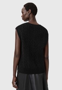 Top de punto negro sin mangas con un patrón texturizado, escote redondeado y corte ligeramente holgado, combinado con una falda de cuero negra.