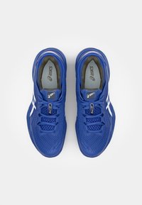 Baskets de sport bleues avec une tige en mesh, bout rond, accents blancs, lacets et semelle intérieure rembourrée. Semelle extérieure en caoutchouc texturé.