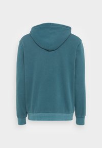 Sweat à capuche en sarcelle, avec manches longues, une texture douce, et des poignets et ourlet côtelés. Design simple sans motifs visibles.