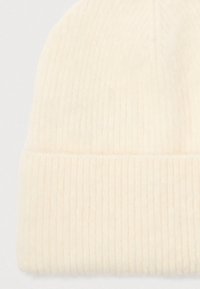 Cremefarvet ribstrikket beanie-hat med foldet kant, vist mod en hvid baggrund.