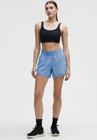 Melnas sporta krūšturis un gaiši zili sporta šorti, kas izgatavoti no viegla auduma. Šortiem ir elastīgs josta un brīvs piegrieziens.