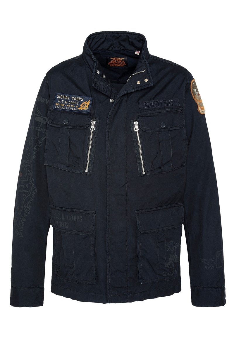 Granatowa kurtka z wysokim kołnierzem, z wieloma kieszeniami z przodu i zamkami błyskawicznymi. Posiada łatki wojskowe i tekstowe detale na rękawach.