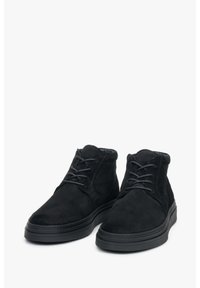 Czarne zamszowe botki za kostkę z okrągłym noskiem, sznurowanym przodem i teksturowaną cholewką. Gruba czarna gumowa podeszwa z minimalnym bieżnikiem.