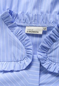 Blusa azzurro chiaro con strisce bianche, dotata di un colletto arricciato e etichetta con la scritta "KAREN BY SIMONSEN", taglia EU 38 e taglia US 8.